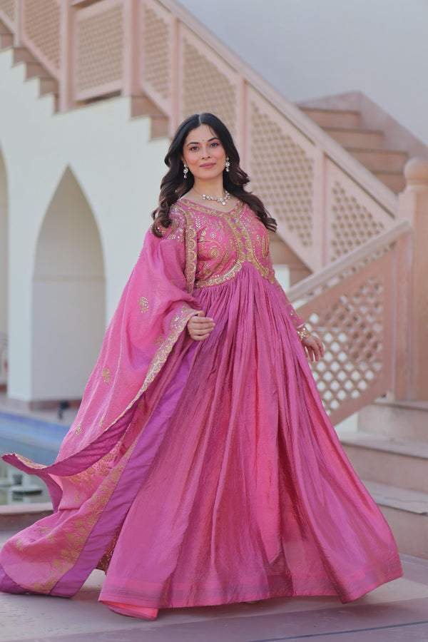 Woman in a pink traditional outfit standing in front of a decorative architectural background